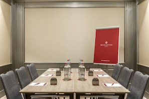 A conference room with a long table, grey upholstered chairs, water bottles, and name cards on the table.