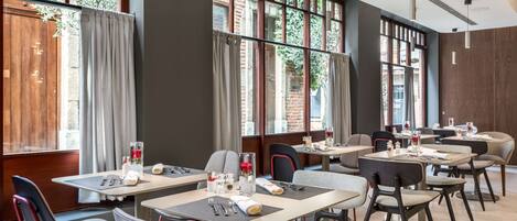 A modern dining area with tables, chairs, and large windows.