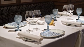 A table set with blue and white plates, clear wine glasses, and a gold-colored candelabra. - NH Collection Brussels Grand Sablon (Brussels)