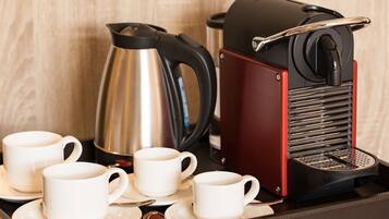 Eine Kaffeemaschine, zwei Tassen, ein Wasserkocher und ein Tablett mit Beilagen.