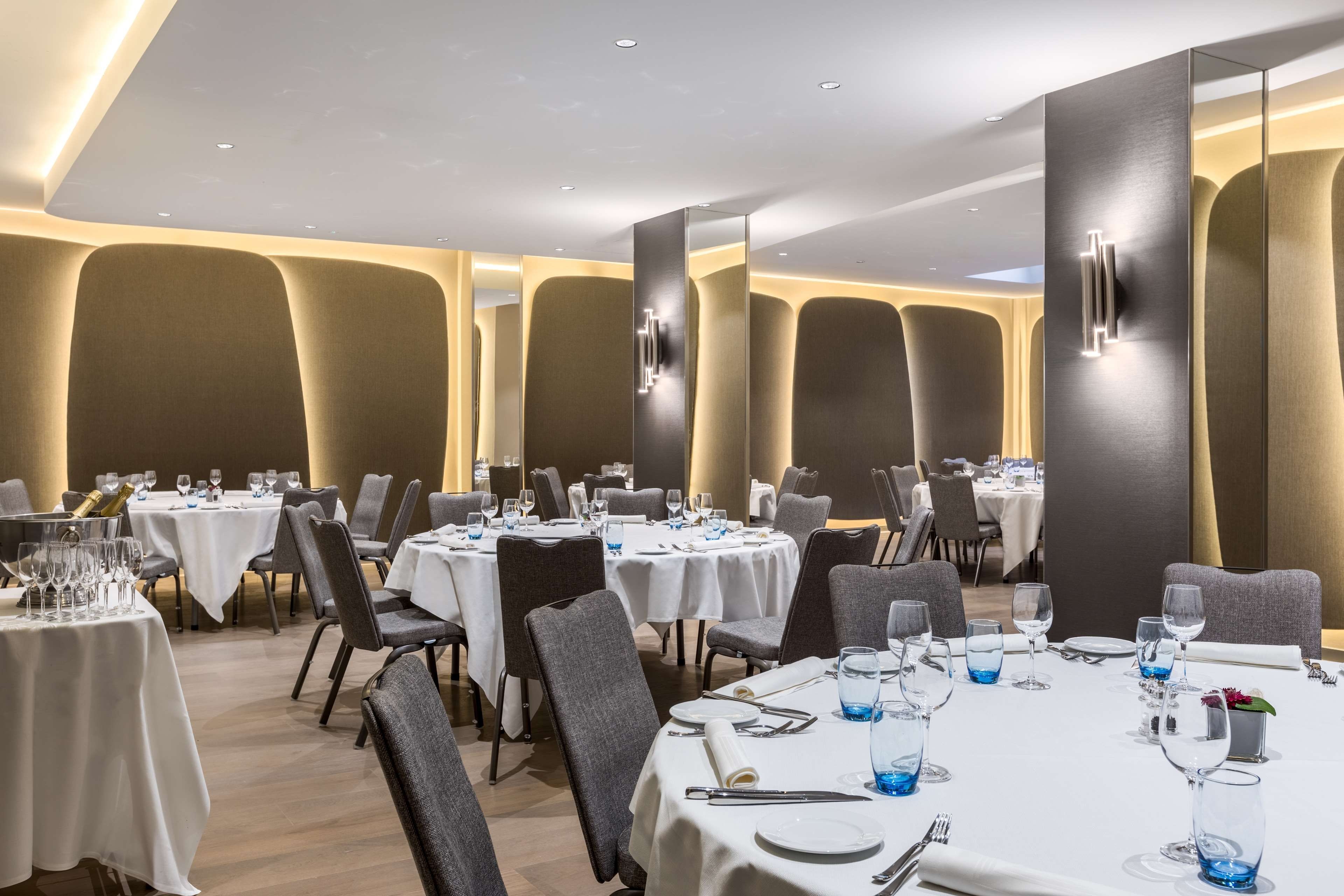 A restaurant with round tables, chairs, and a modern interior design.