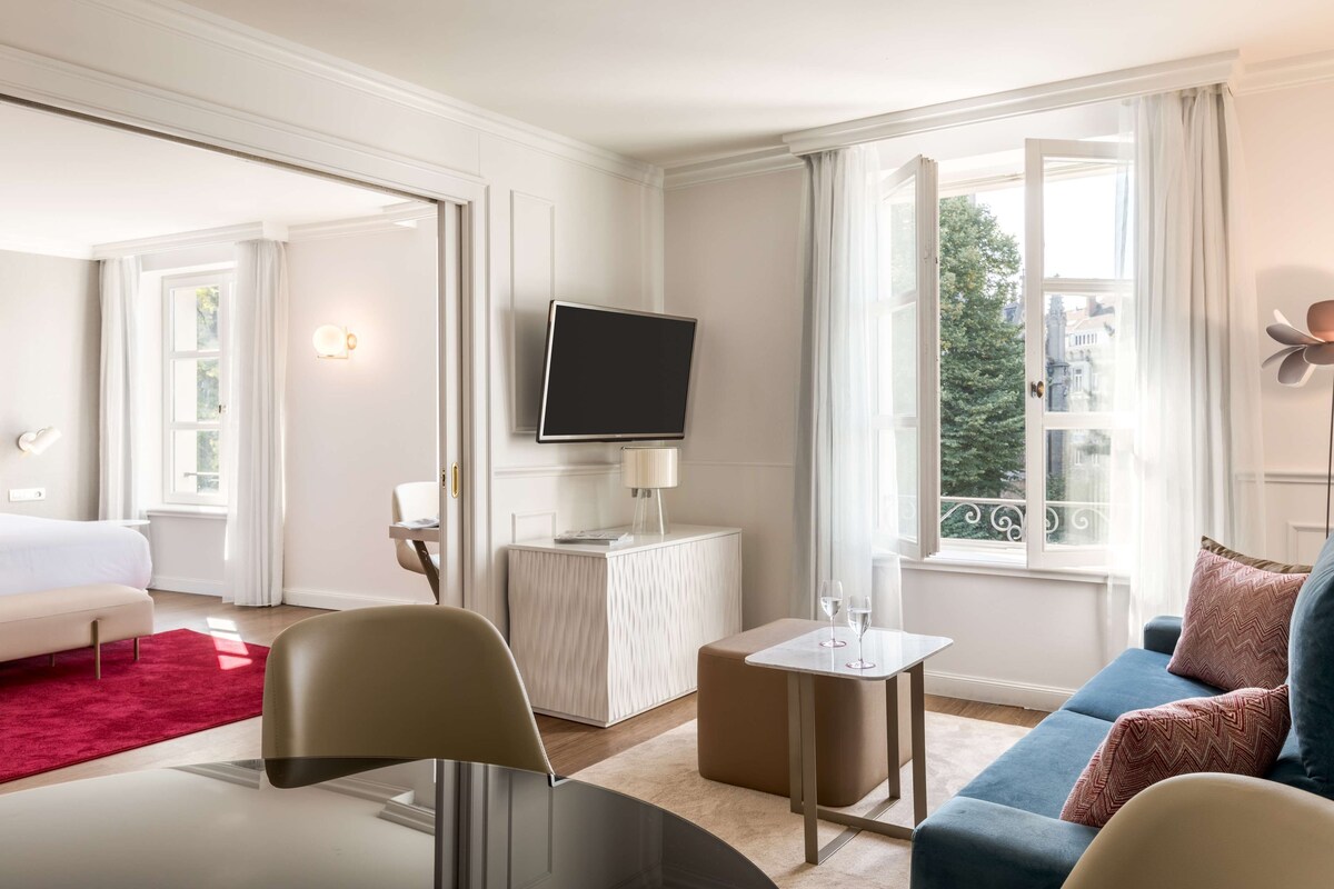 Una camera d'albergo con un letto, una televisione, un tavolino, un divano e una finestra vista.