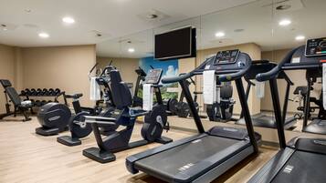 A gym with treadmills, weight machines, and dumbbells.