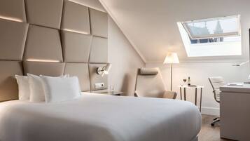 Een moderne hotelkamer met een groot bed, een bureau, een stoel, een lamp en een dakraam.