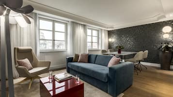 Uma sala de estar moderna com um sofá azul, uma mesa de centro vermelha e um espaço de jantar com mesa e cadeiras.
