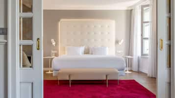 Een slaapkamer met een groot bed, nachtkastjes, een bankje en een rood vloerkleed.