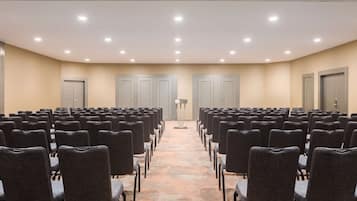 A conference room with rows of chairs, a podium, and doors.