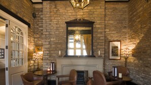 Una habitación con paredes de piedra, chimenea, sillones de cuero y una mesa.