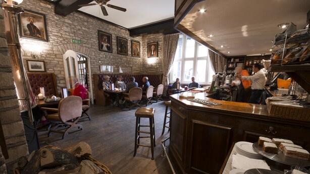 Un restaurante con paredes de piedra, suelos de madera y una zona de bar con taburetes y mostrador.