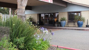 A building entrance with a 10ft clearance sign, potted plants, and a bench outside.
