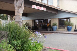 A building entrance with a 10ft clearance sign, potted plants, and a bench outside.