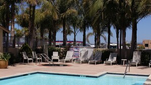 A swimming pool with lounge chairs and palm trees.