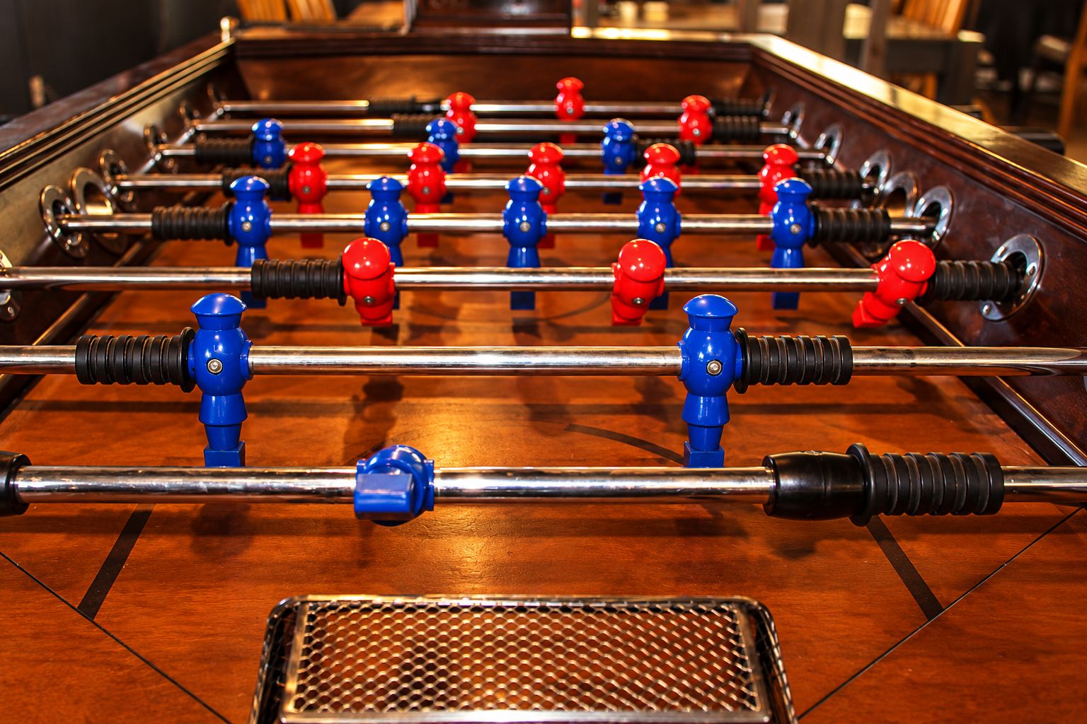 A foosball table with metal rods and red and blue player figures.