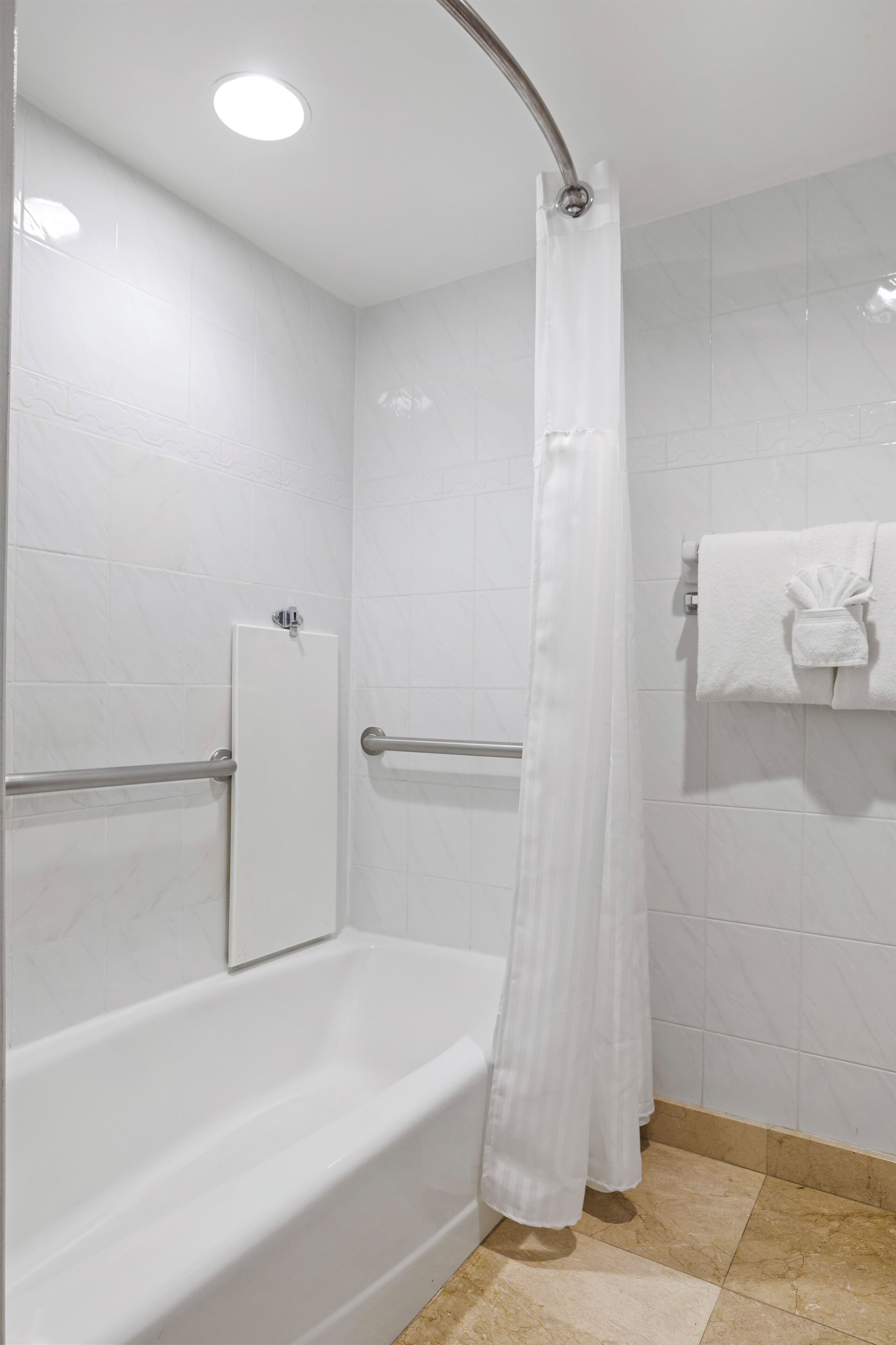 Un baño moderno con una bañera blanca, una cortina de ducha y un perchero con una toalla.