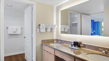 Un baño con dos lavamanos, un espejo grande y un perchero con varias toallas.