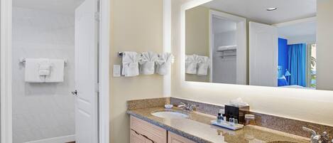 A bathroom with two sinks, a large mirror, and a towel rack with multiple towels.