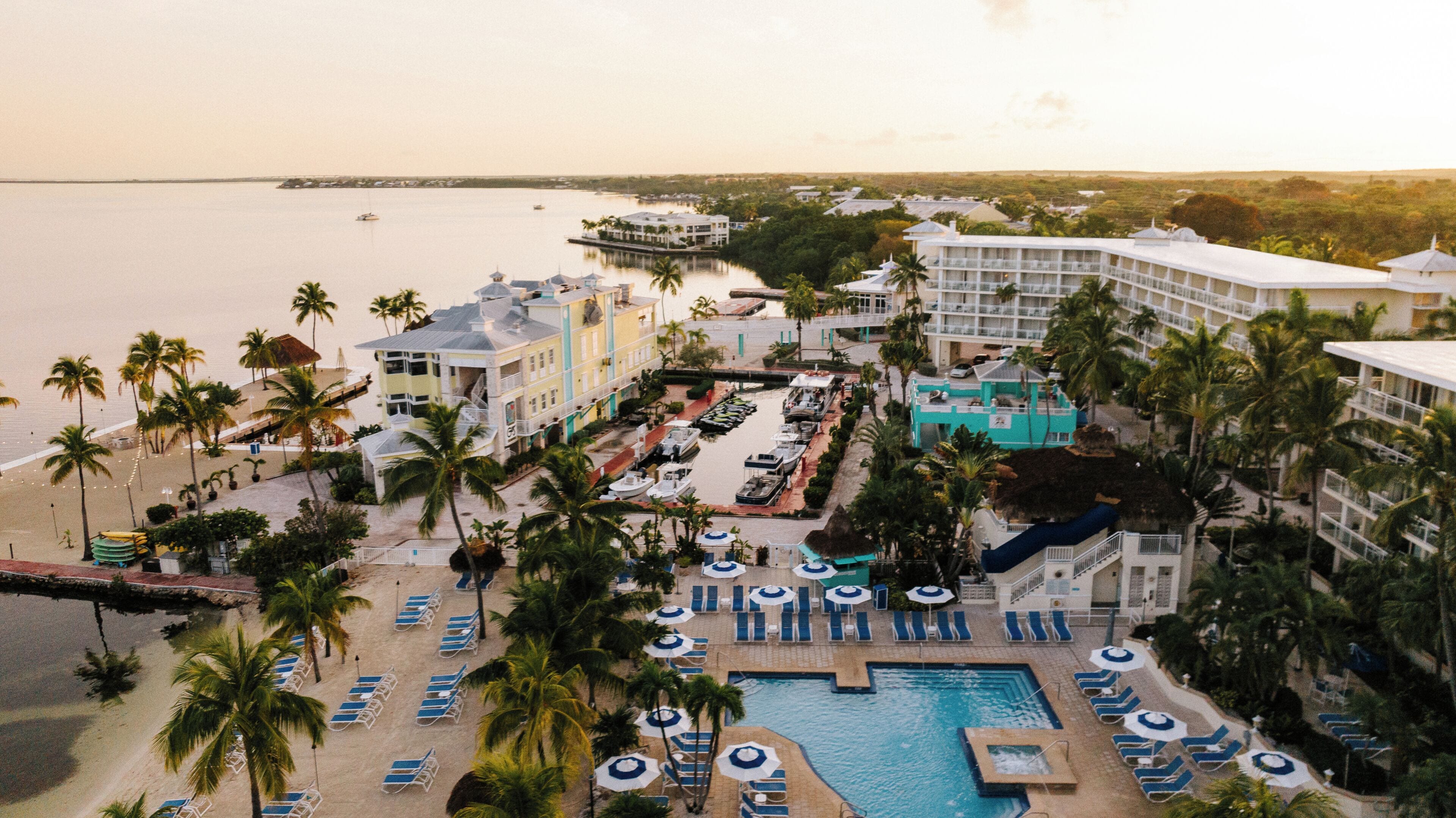 A resort with a swimming pool, lounge chairs, and a view of the sea.