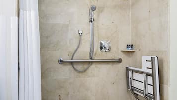 A shower area with a grab bar, a showerhead, and a shelf with toiletries.