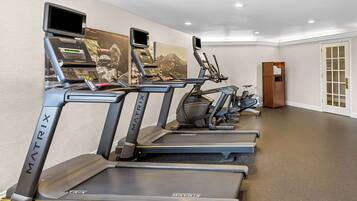 A row of MATRIX treadmills in a hotel fitness room with a large wall mural and a wooden door.
