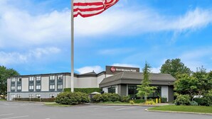 Un hotel Best Western Plus con asta de bandera, estacionamiento y jardines bien cuidados.