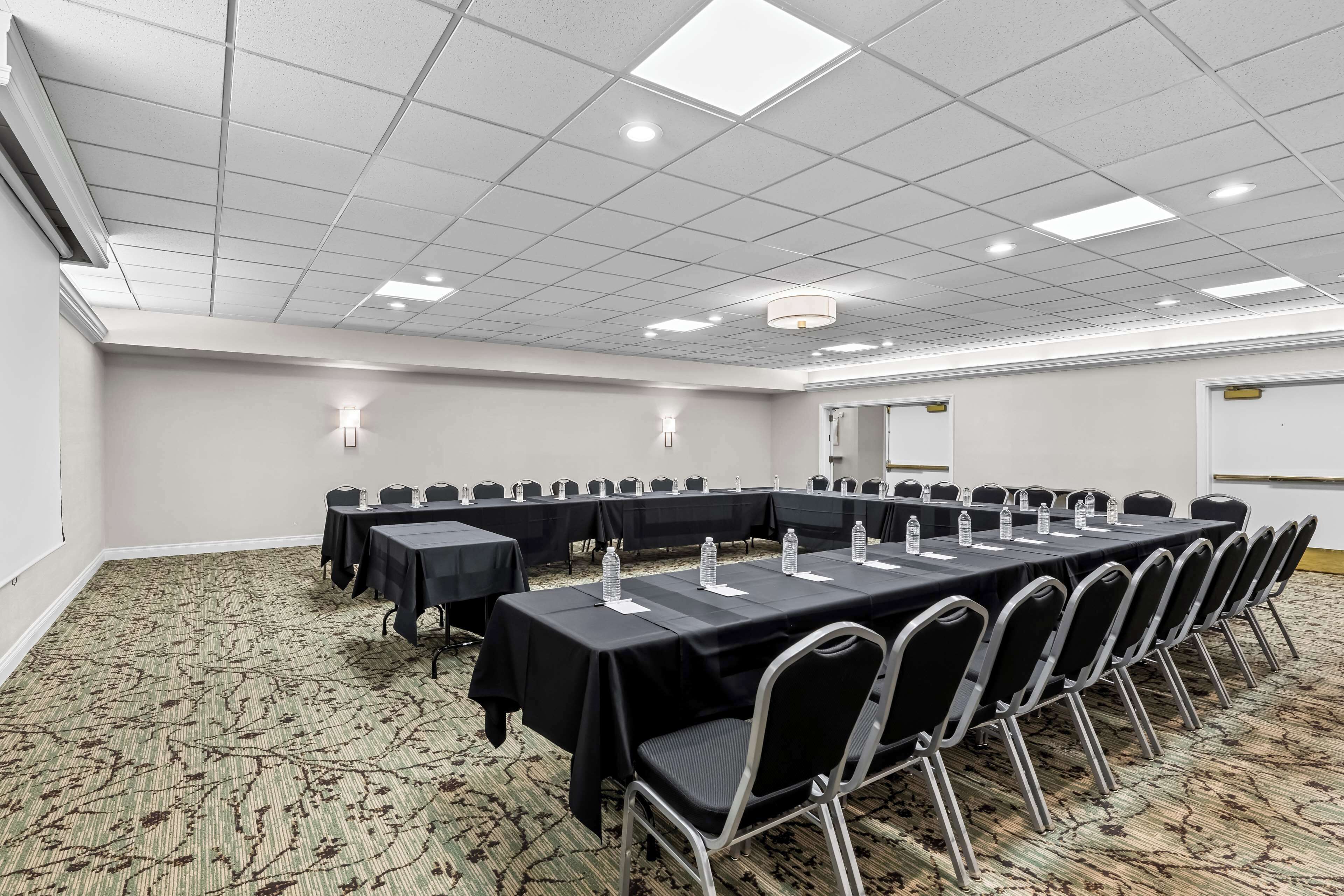 Un salón de conferencias con una larga mesa, sillas y botellas de agua.