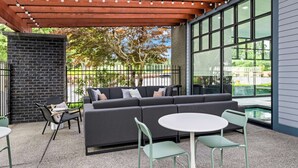 Un espacio al aire libre con un sofá gris, dos sillones y una mesa redonda.