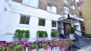 A hotel with a white facade, a sign reading "HOTEL KENSINGTON COURT," and a staircase leading to the entrance. - Kensington Court Hotel (London)