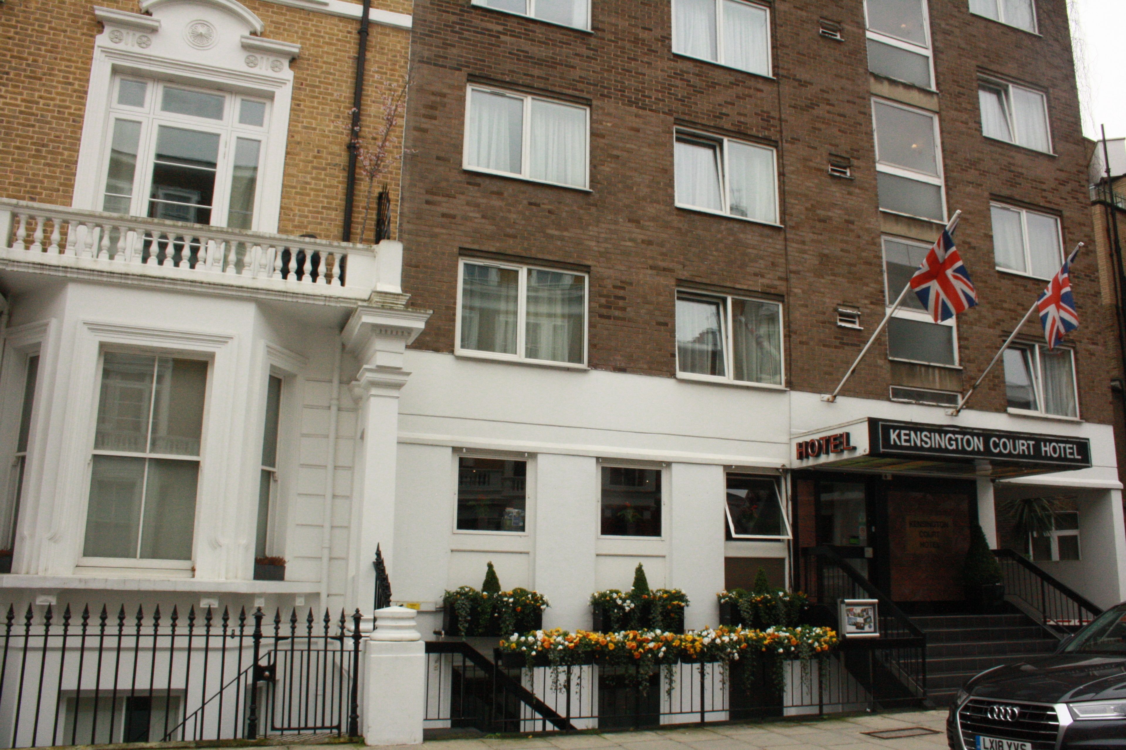 A hotel with a traditional facade, featuring a prominent entrance with a staircase and a sign reading "Kensington Court Hotel".