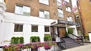 A hotel with a sign reading "Kensington Court Hotel," featuring a staircase leading to the entrance, a white facade, and multiple windows. - Kensington Court Hotel (London)