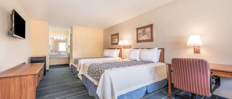 A hotel room with two beds, a desk, a chair, a TV, and a bathroom visible in the background.