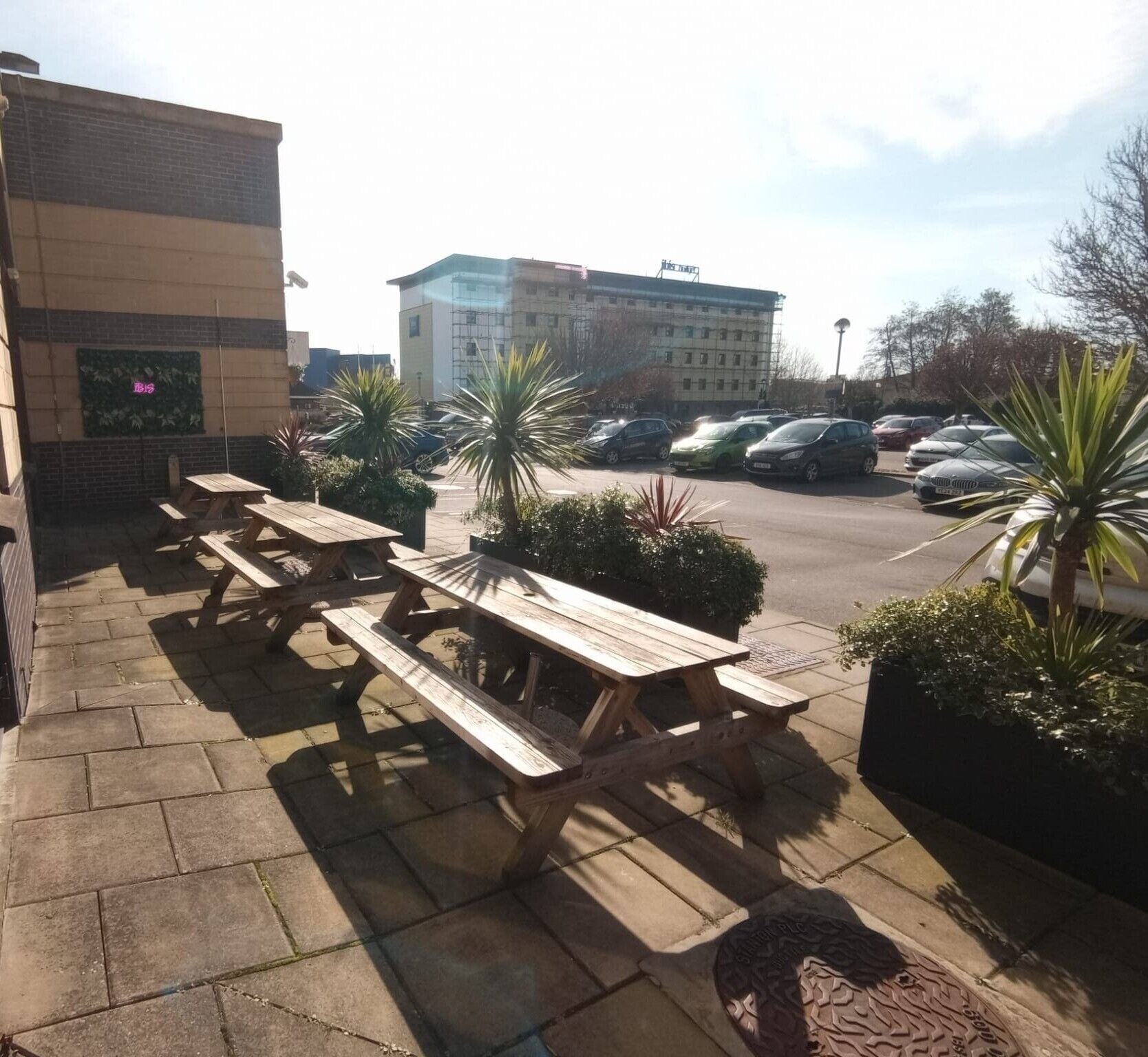 An outdoor patio area with picnic tables and potted plants.