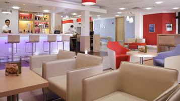 A modern interior with bar seating, a reception area, and a seating area with tables and chairs.