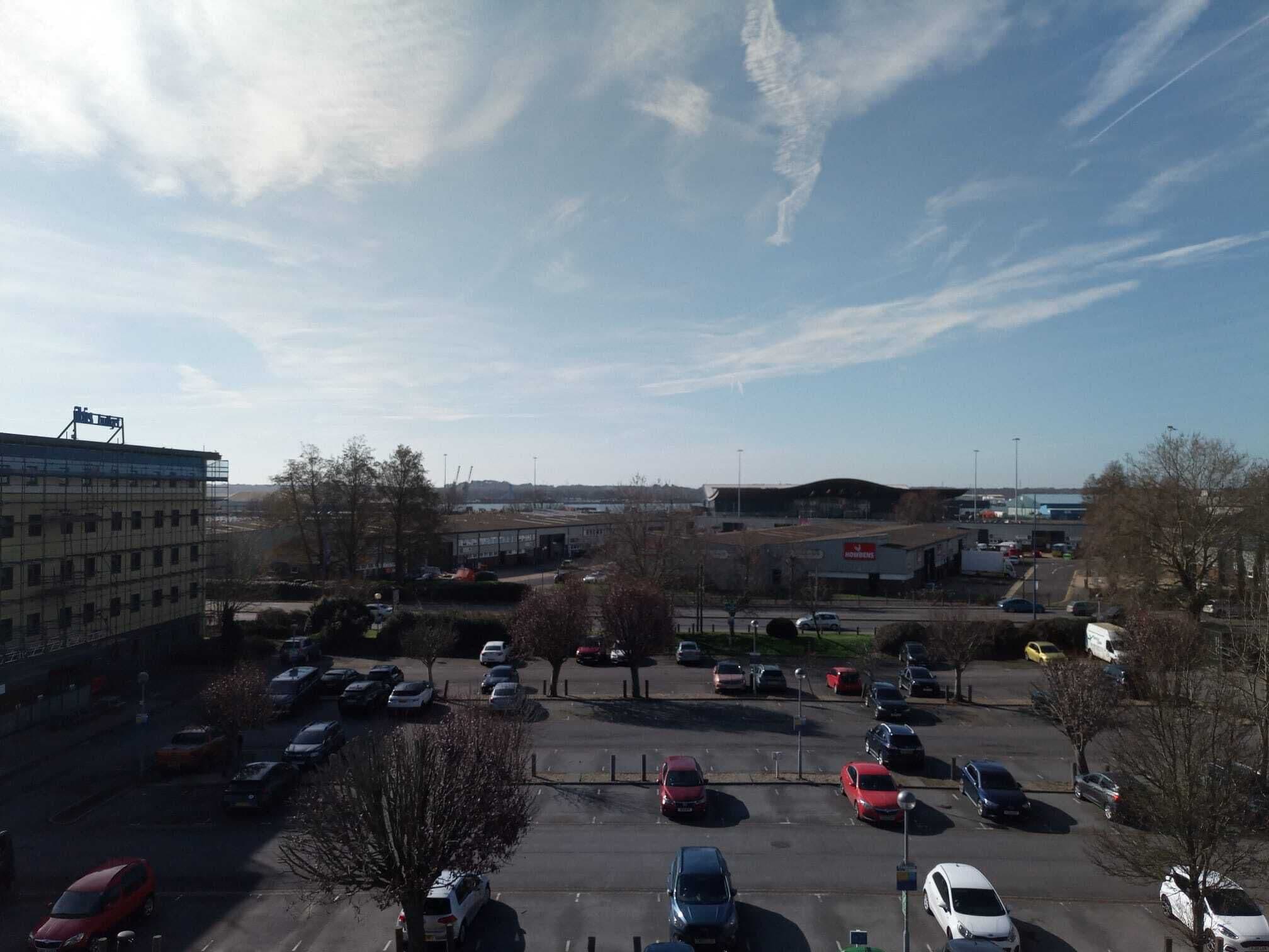 A parking lot with multiple cars and a building in the background.