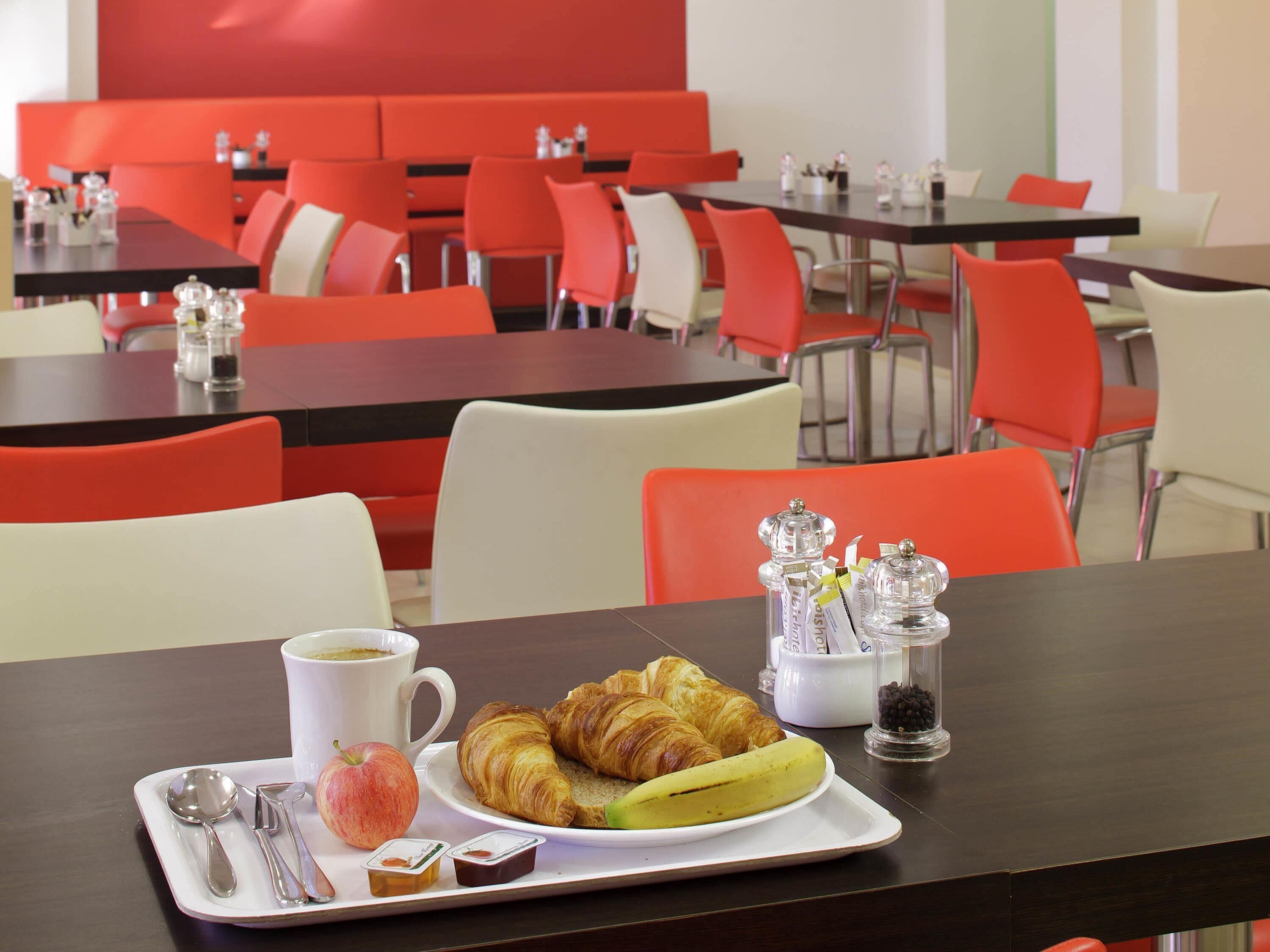 A dining area with tables and chairs, a tray with food and drink, and salt and pepper shakers.