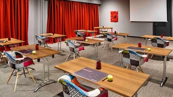 Una sala de conferencias con mesas, sillas y una pantalla para proyector.
