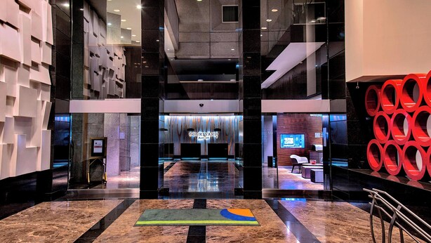 Un moderno vestíbulo de hotel con suelo de mármol, una recepción y una escalera.