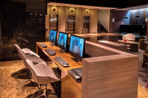 Una hall d'albergo moderna con una reception, diversi monitor per computer e un'area relax.