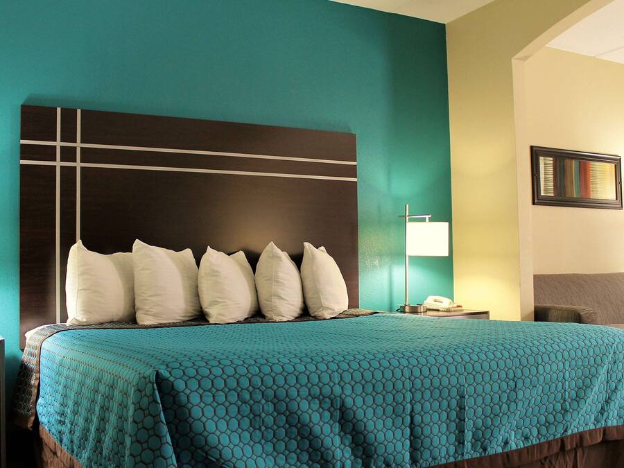 A hotel room with a bed, a nightstand, a desk, a chair, and a sofa.