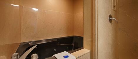 A bathroom with a black bathtub, a white towel, and a shower door.