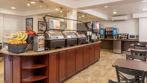 A breakfast bar with a variety of food items, a coffee machine, and a microwave. - Best Western Plus Raffles Inn & Suites (Anaheim)