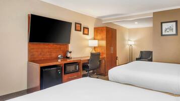 Een hotelkamer met twee bedden, een bureau met een flatscreen televisie, een magnetron, een koffiezetapparaat en een stoel.