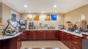 Una cocina de hotel con un montaje tipo bufé, que incluye una estación de autoservicio, una máquina de café y un refrigerador.