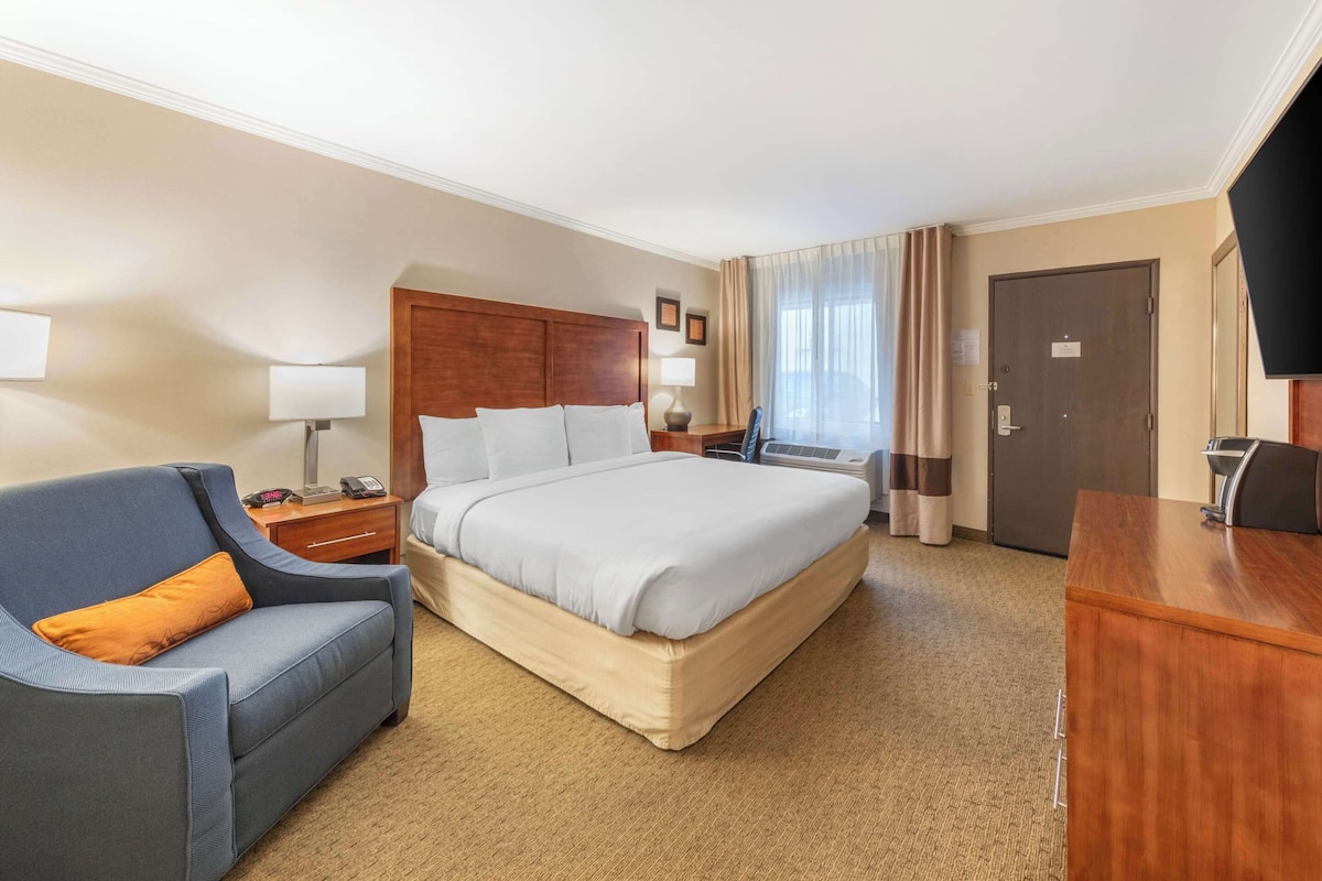 A hotel room with a bed, a desk, a chair, and a television.