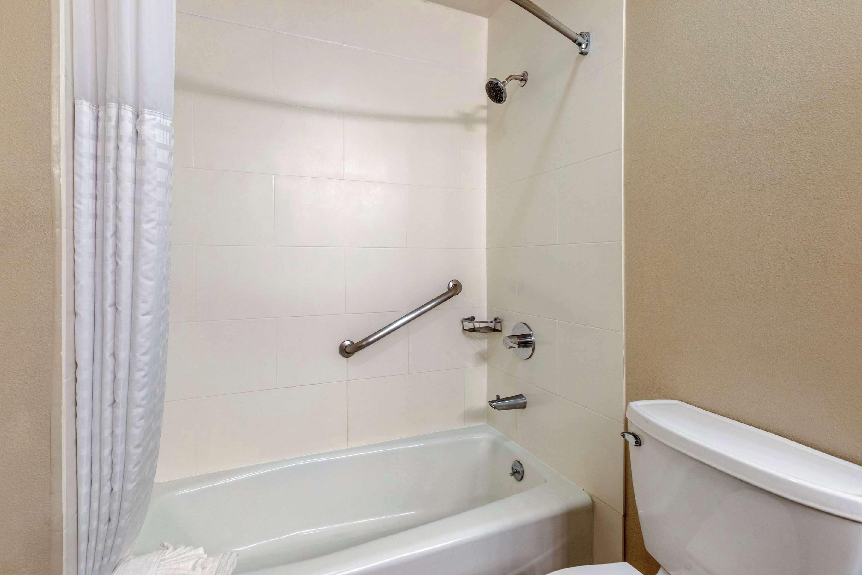 A bathroom with a bathtub, a toilet, and a shower area.