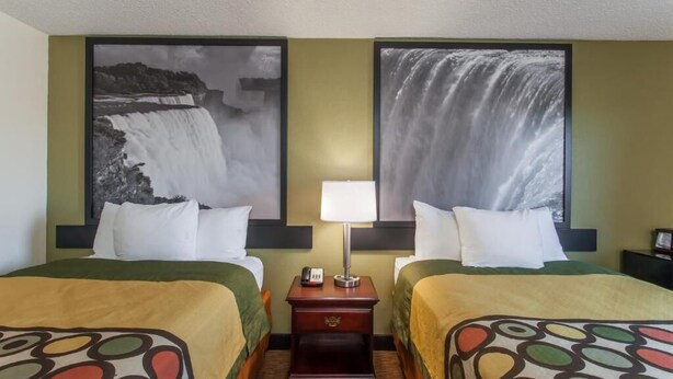 A hotel room with two beds, a nightstand with a lamp, and two large waterfall photographs on the walls. - SuperB Hamburg Motel (Hamburg)
