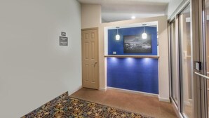 A hallway with a patterned carpet, a door, a blue accent wall, and a framed picture. - SuperB Hamburg Motel (Hamburg)