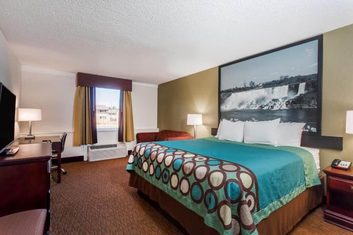 A hotel room with a bed, desk, and a large window.