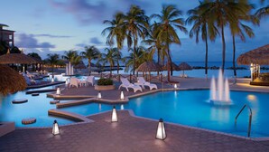 A pool area with lounge chairs, palm trees, and a water fountain.