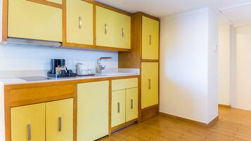 Cocina con armarios amarillos, encimera blanca y pileta de acero inoxidable.
