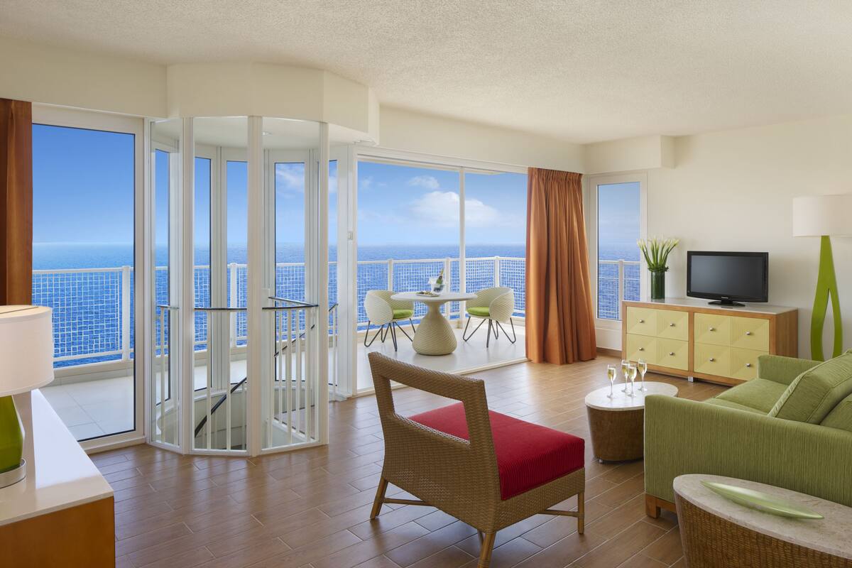 A spacious living room with a balcony, a television, and a dining area with a table and chairs.
